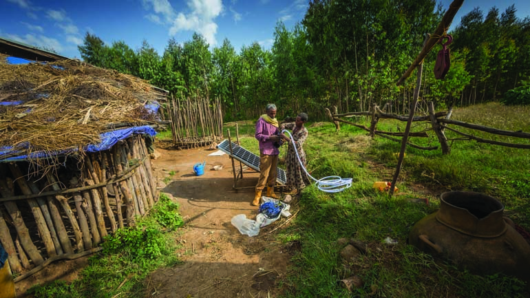 Two people working on irrigation equipment in village