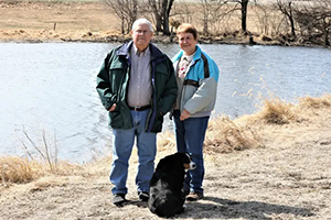 Two people standing by lake