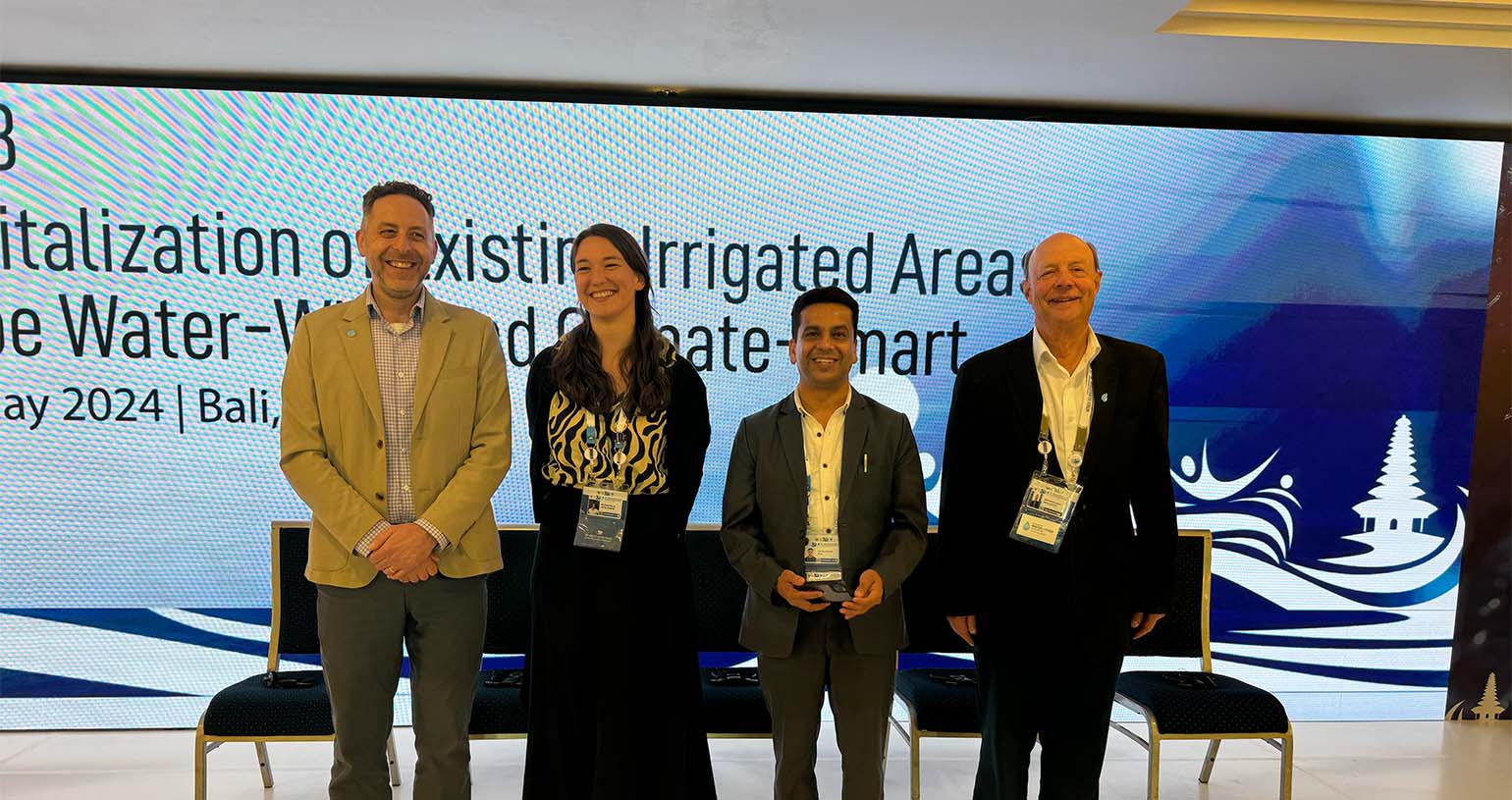 Four people standing in front of large screen
