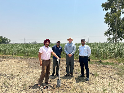 Four people standing in front of agriculture field