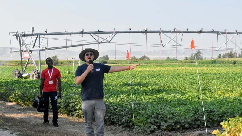 Two people standing in front of center pivot in field