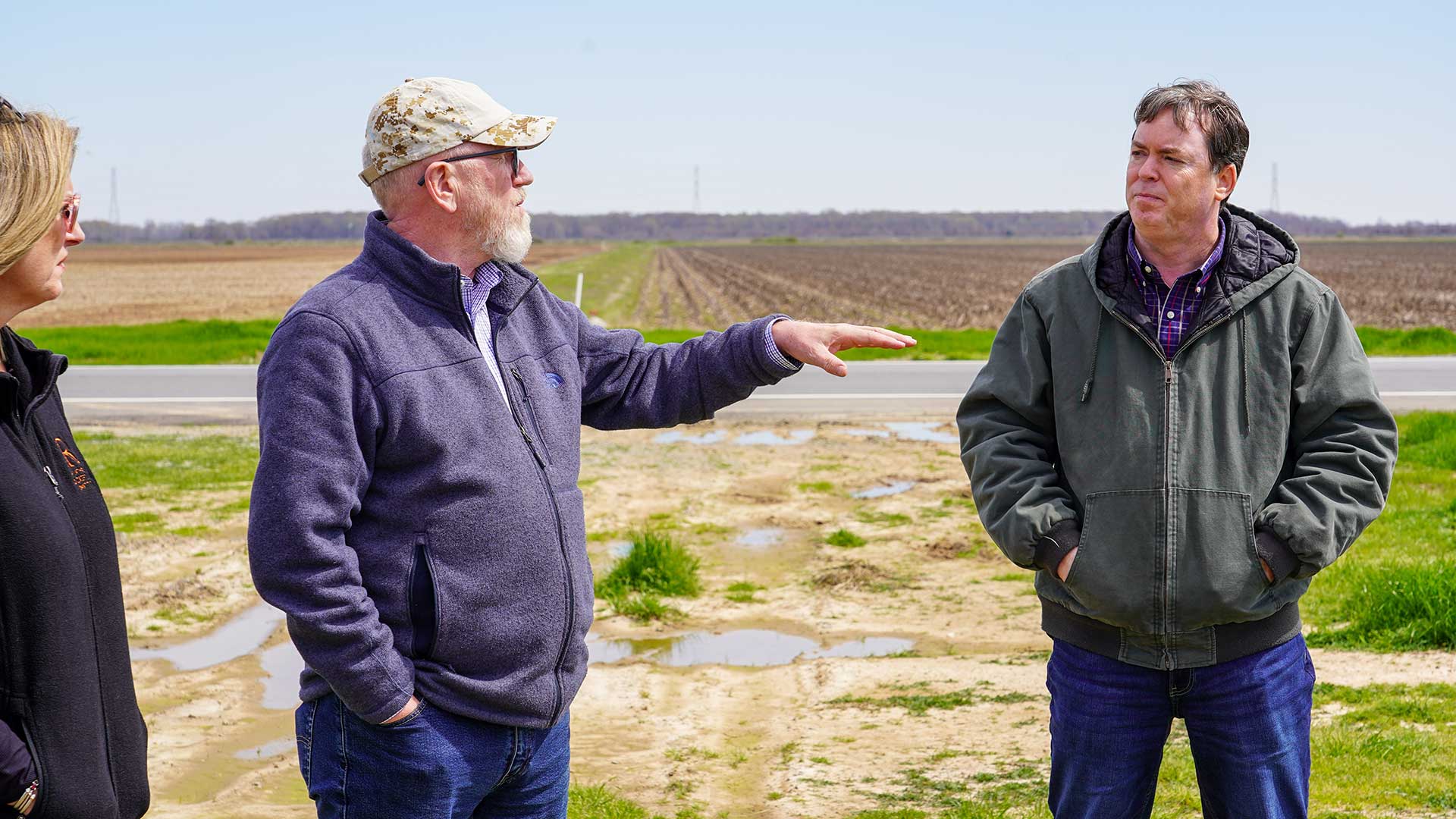 Three people talking on edge of field