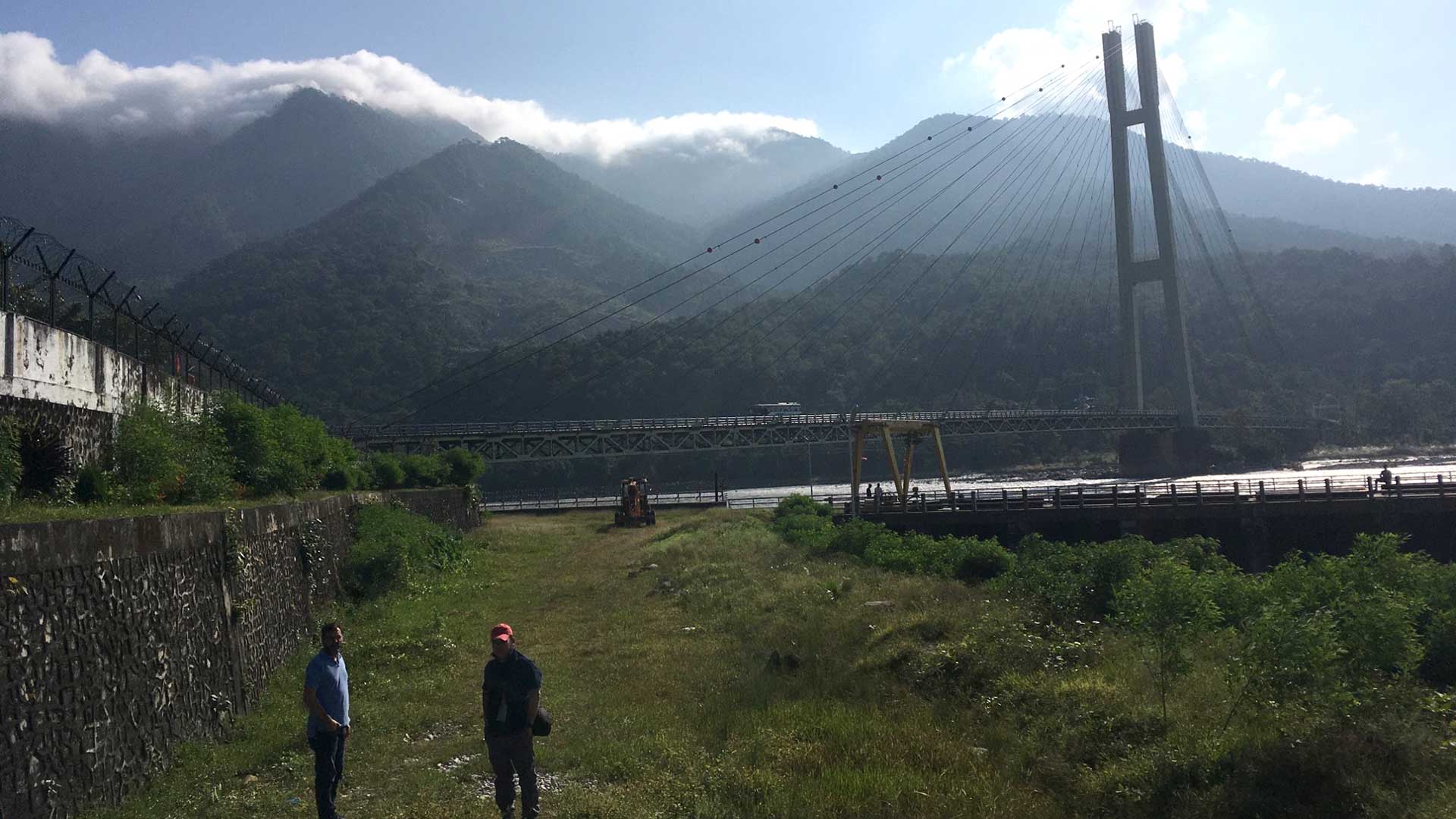 Two people with large bridge and water in background