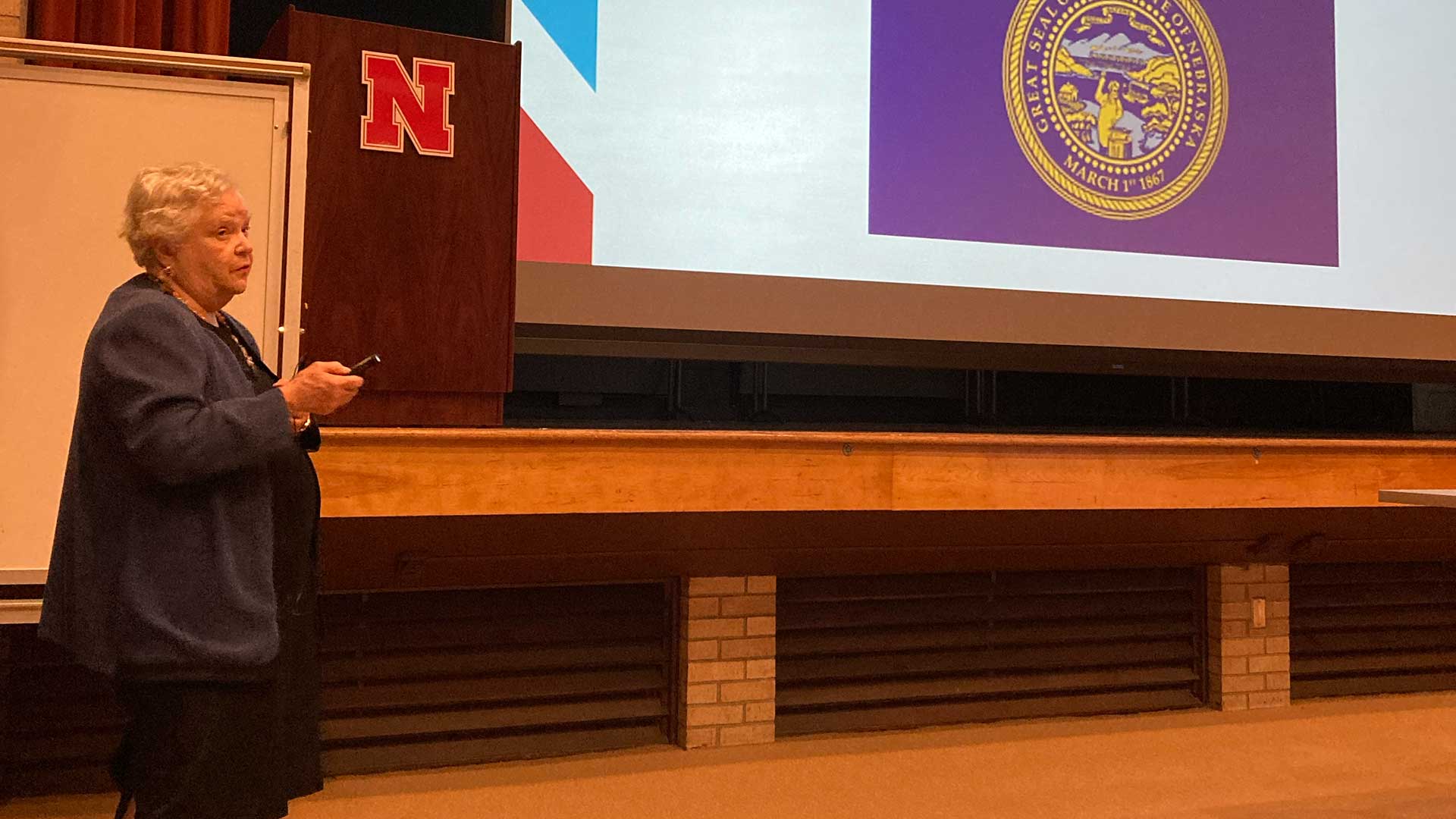 Person standing beside large presentation screen