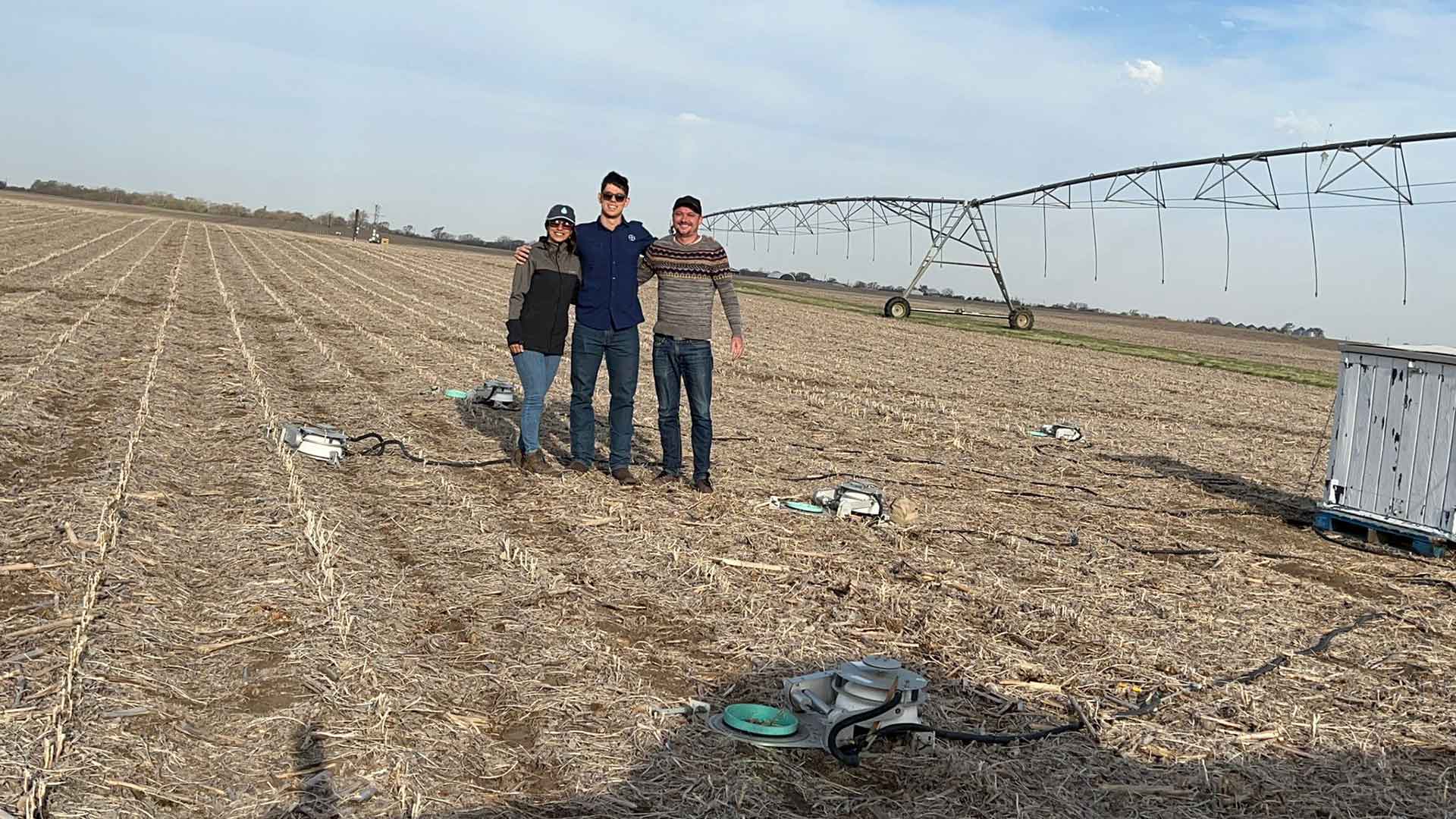 Three people standing in empty field