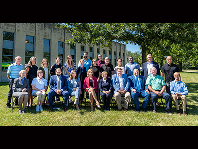 Group sitting on chairs outdoors in front of building