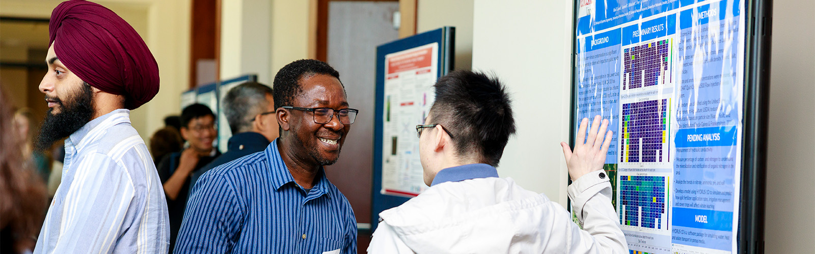 Two people talking in front of poster