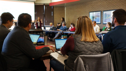 People sitting at table in room listening to speaker