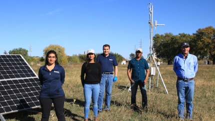 People standing in front of scientific equipment in field