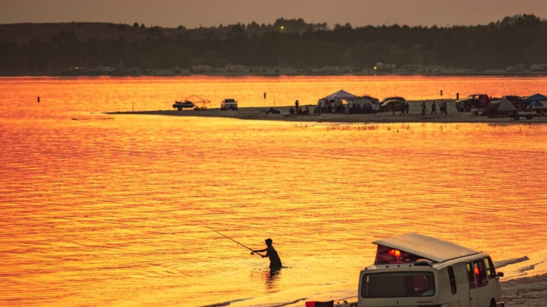 Person fishing on lake in evening