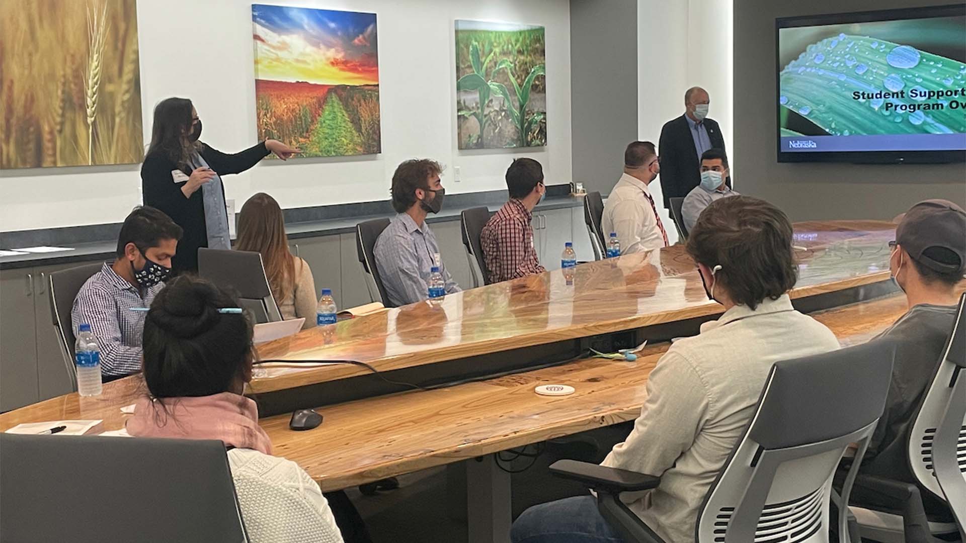 People sitting around table listening to presentation