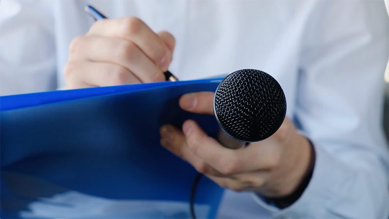Person taking notes while holding microphone