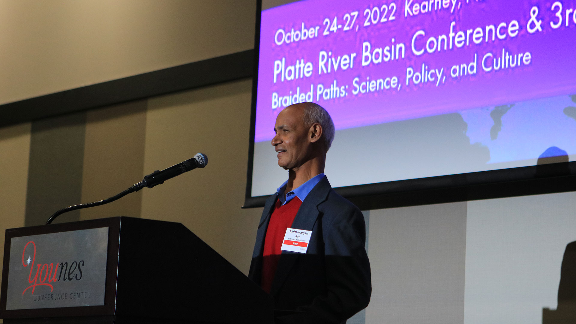 Person speaking at podium with presentation screen in background