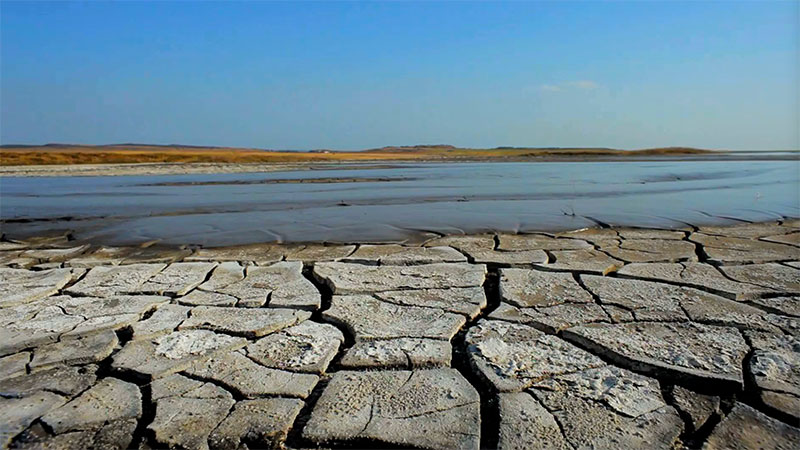 Cracked soil with lake in background
